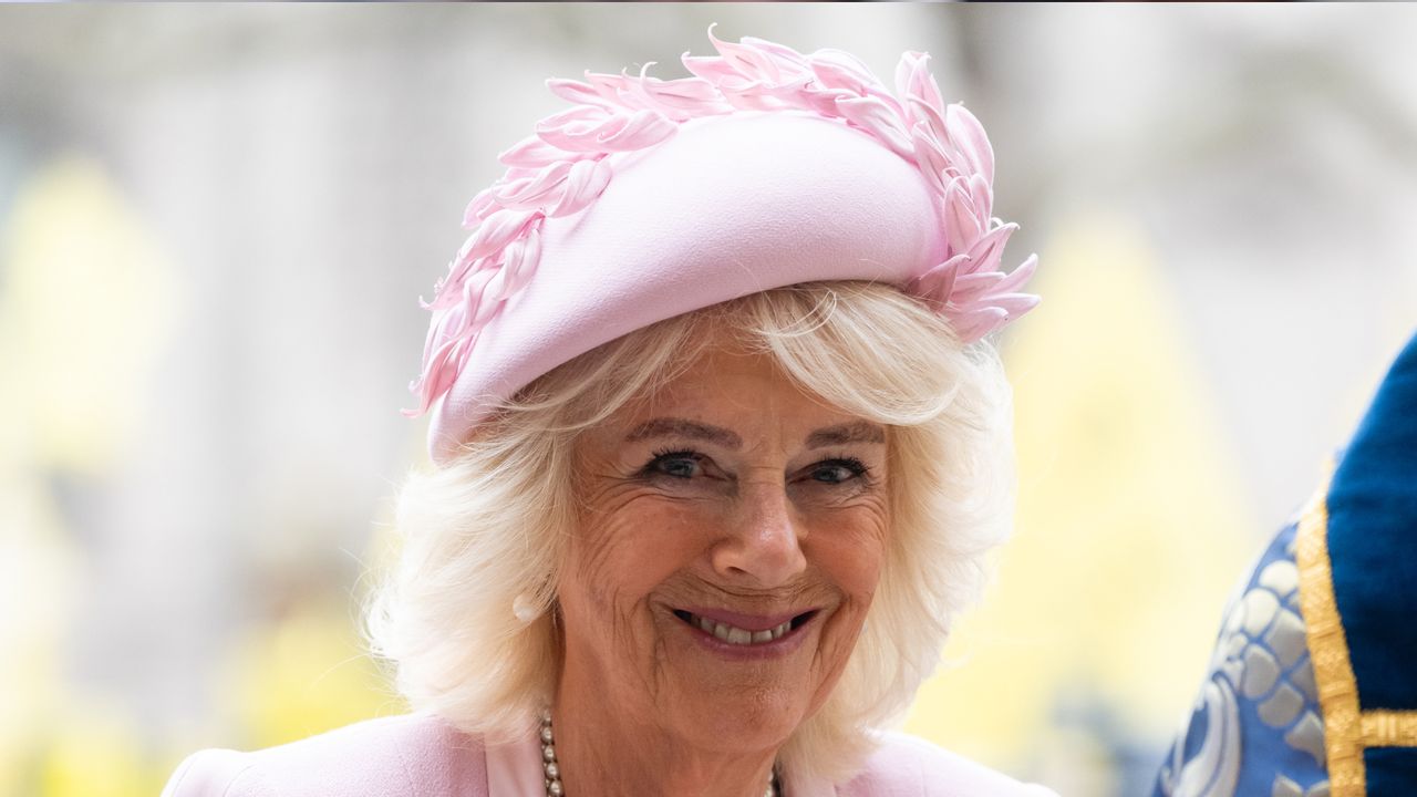 Queen Camilla wearing a pink hat and coat and smiling at the camera on Commonwealth Day 2025