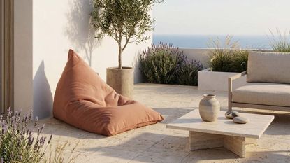 Image of a terracotta orange bean bag in a neutral, luxury outdoor seating area.