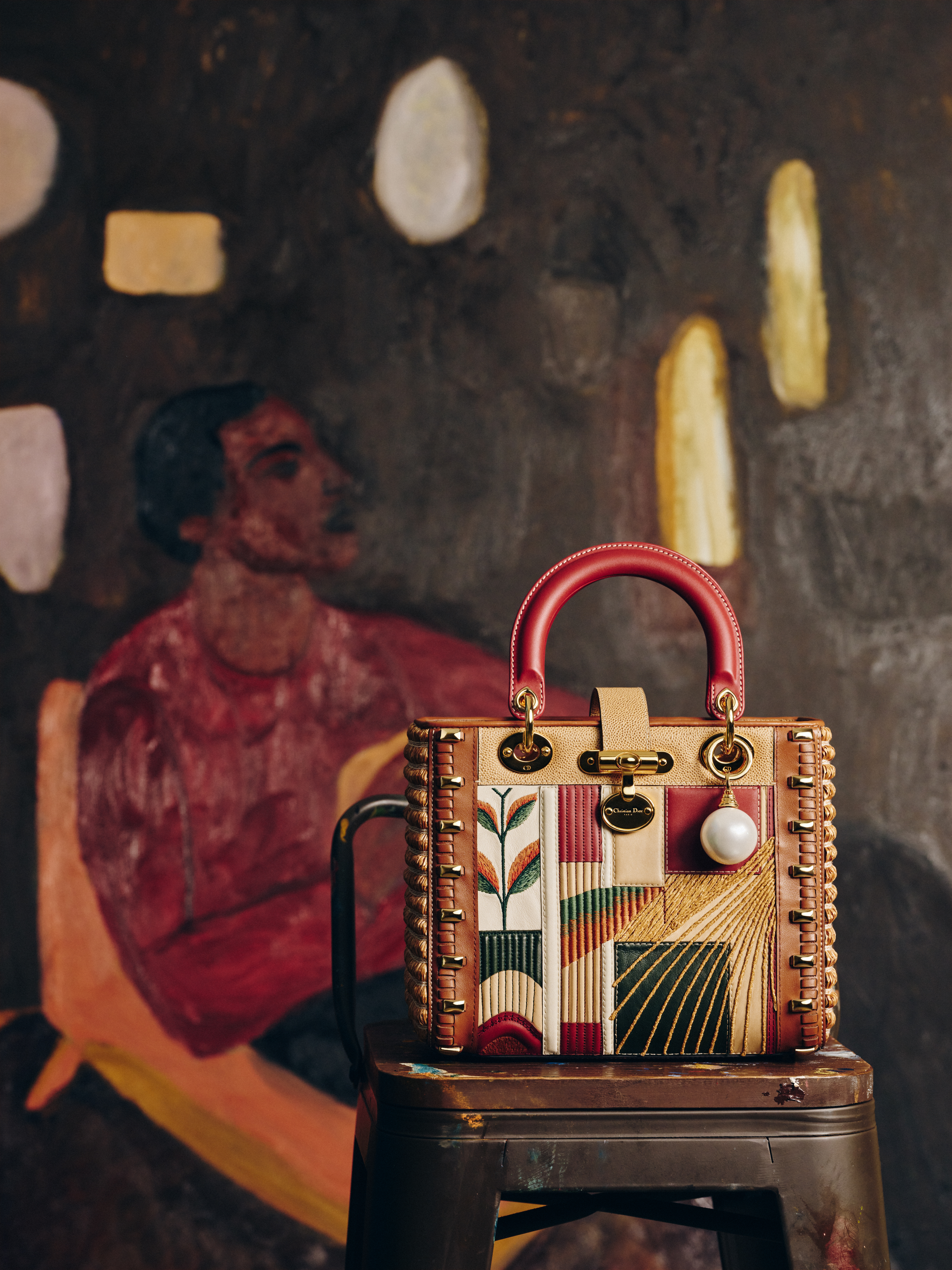a multitexture lady dior art bag in front of a painting