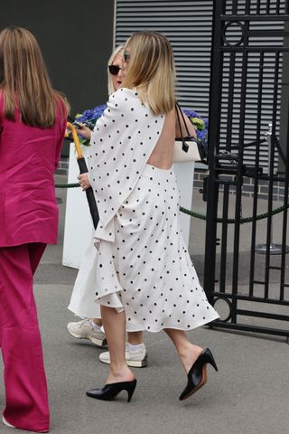 Margot Robbie enters Wimbledon in a backless polka dot dress with an east west bag and black mule heels