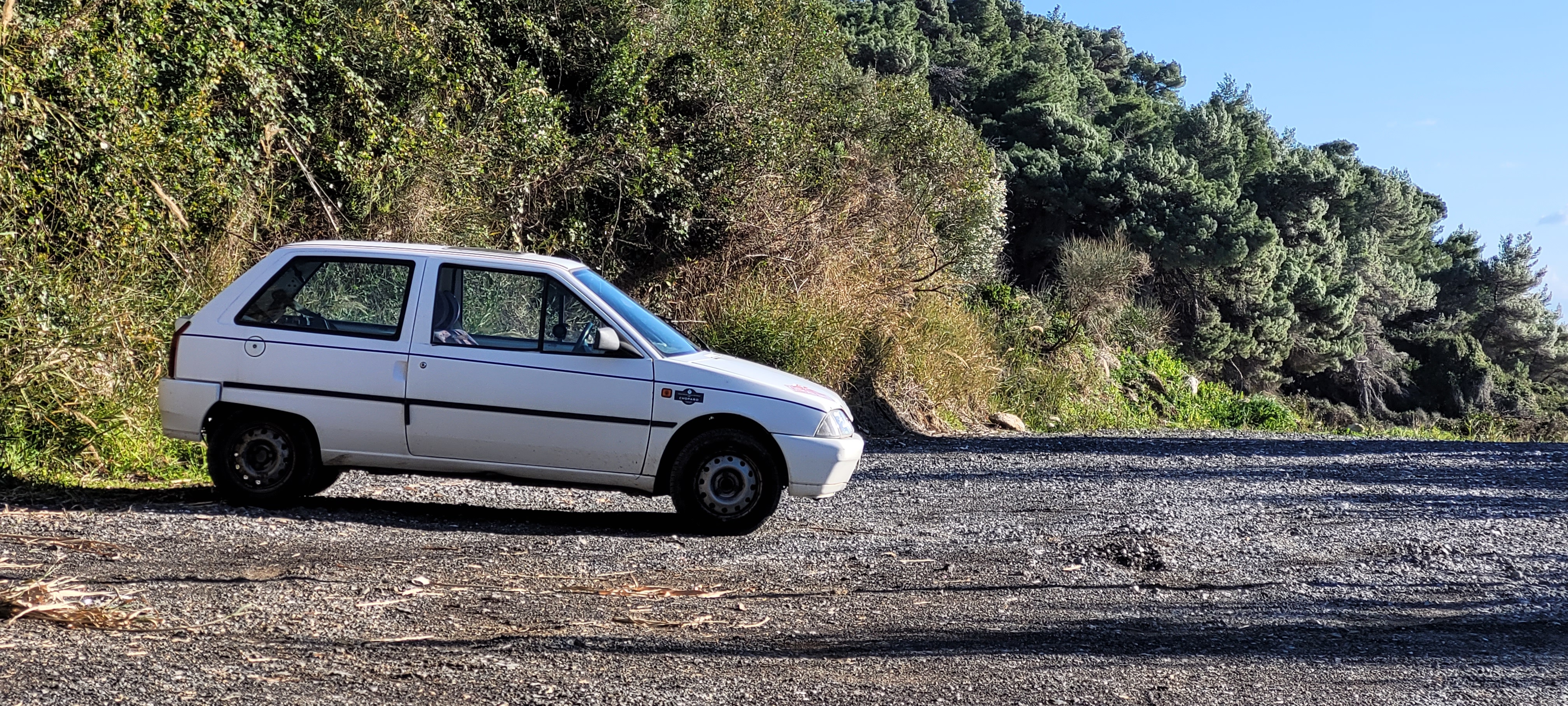 A knackered old white Citroen AX. It looks like a rusty metal box
