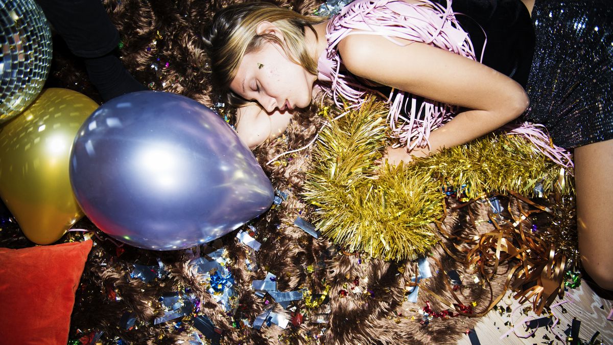 A woman with blonde hair falls asleep on the floor after a New Year&#039;s Eve party has ended