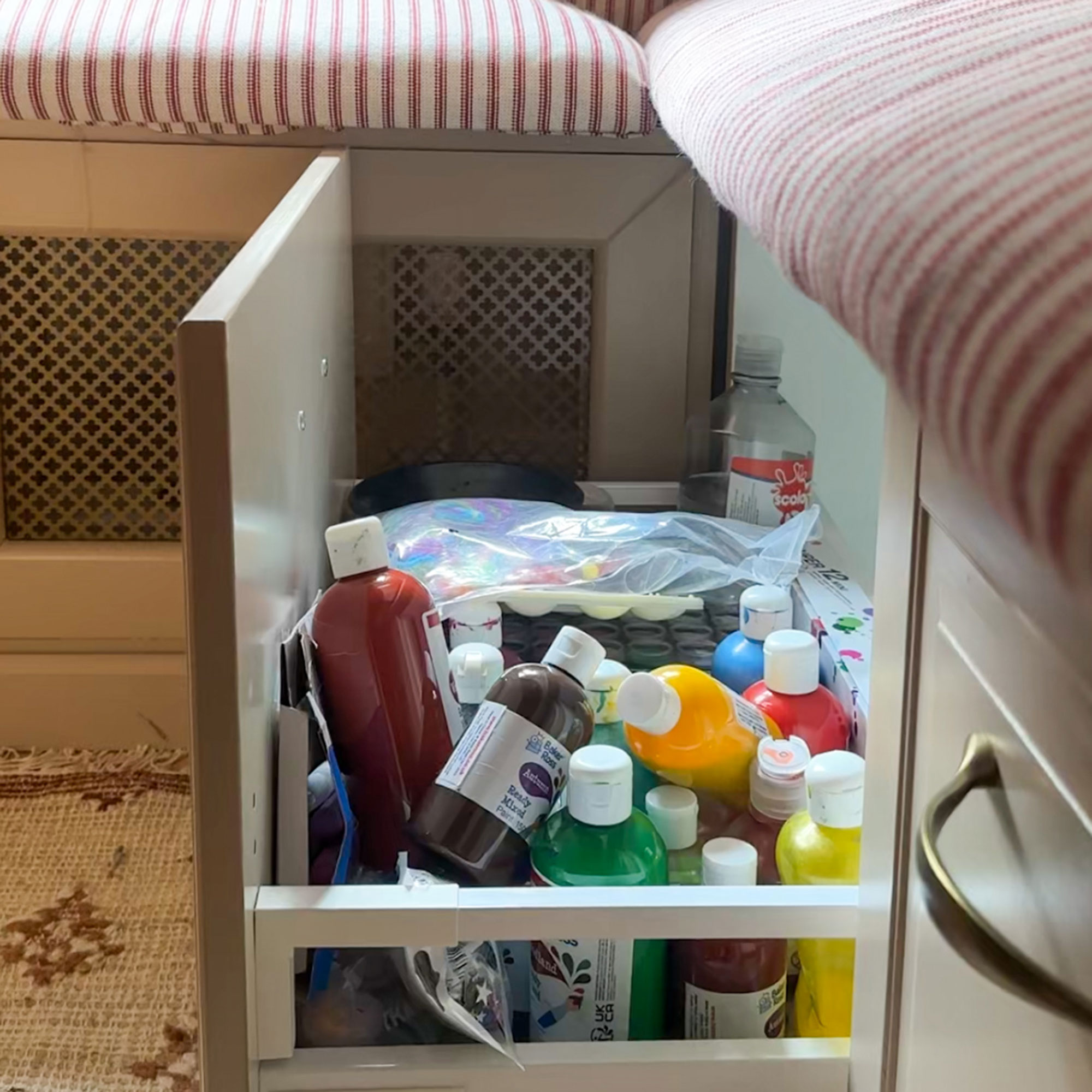 Drawer of medicine underneath seat of kitchen banquette with striped upholstery