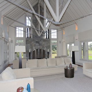 A large, open, white living room with vaulted ceilings and exposed beams