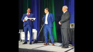 Grass Valley Executive Chairman Louis Hernandez Jr., l., presents CEO Jon Wilson with the “key” to the Grass Valley Media Universe as Sinclair’s Del Parks looks on.