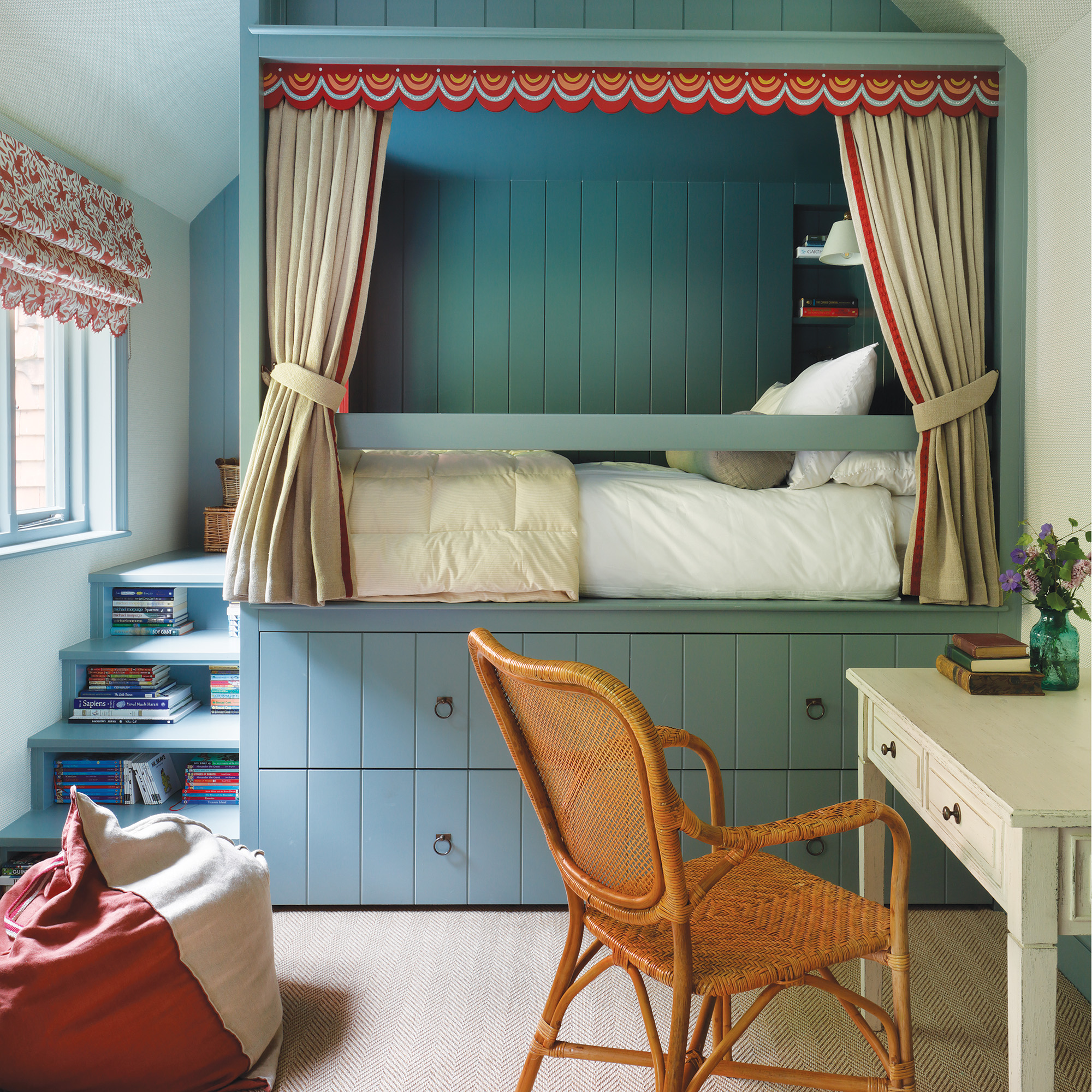 a blue fitted bed in children's bedroom with a curtain, trim, two drawers beneath the bed and steps up the left with books stored underneath