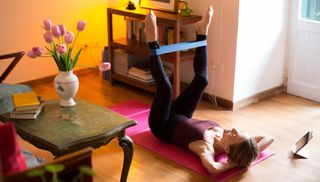 Woman lying on her back exercising with a resistance band