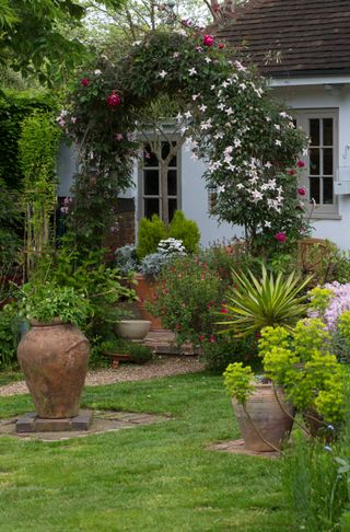 rose and jasmine arch in garden with garden room