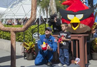 At NASA’s Kennedy Space Center Visitor Complex in Florida, NASA astronaut Don Pettit uses a giant slingshot to launch a plush Angry Bird character during the grand opening of the new Angry Birds Space Encounter. Standing behind Pettit is Red Bird, one of the Angry Bird characters. Image was released March 22, 2013.