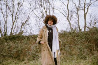 Portrait photo of a girl with an afro wearing an afghan coat with white scarf