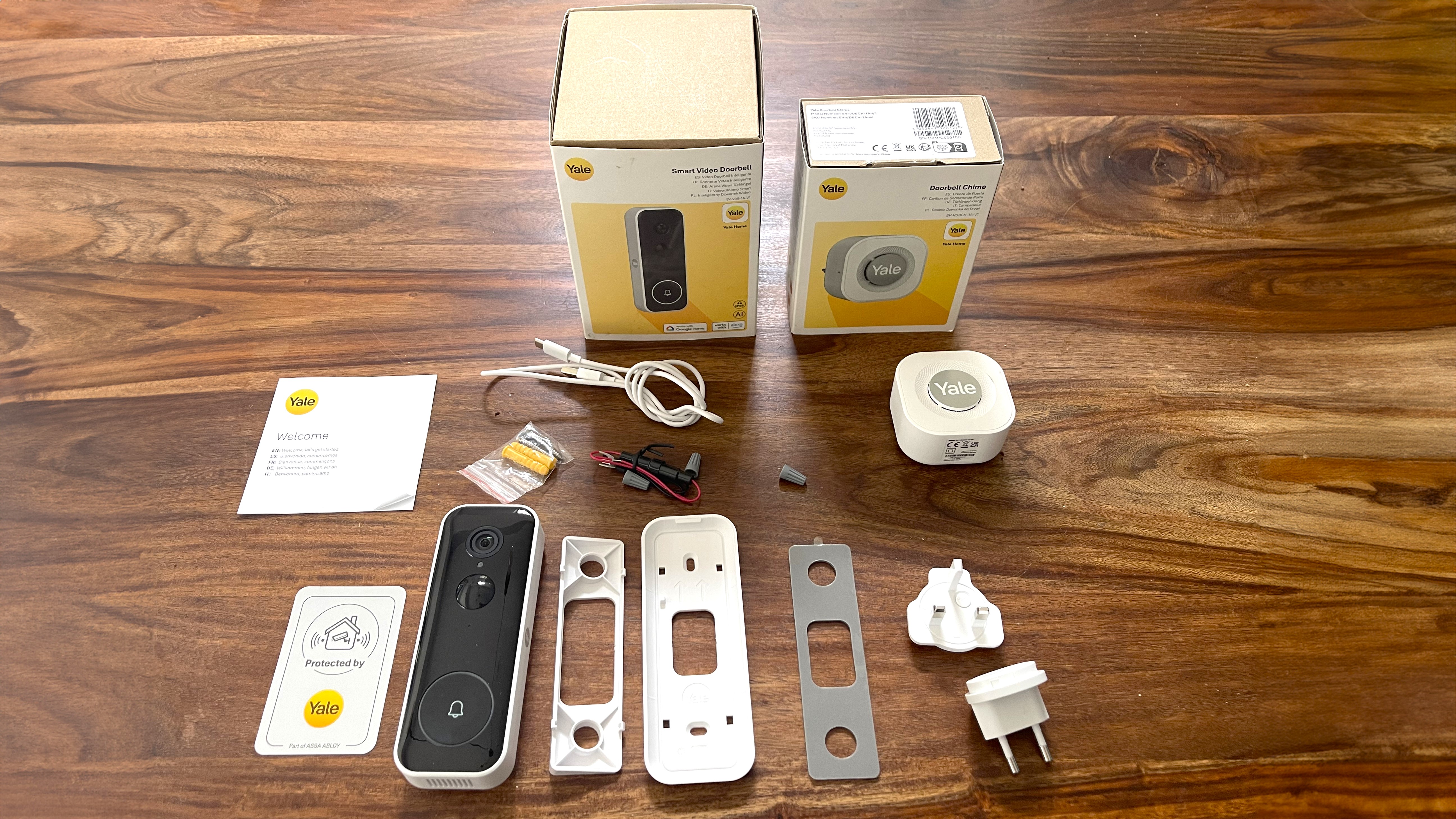 Yale Smart Video Doorbell and accessories on a wooden floor