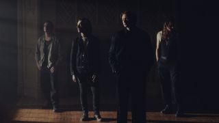 Bad Omens standing in a line in a house looking grumpy