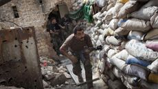 Syrian rebels take cover behind a barricade in Aleppo