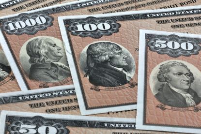 U.S. series EE savings bonds in different denominations layered over each other.