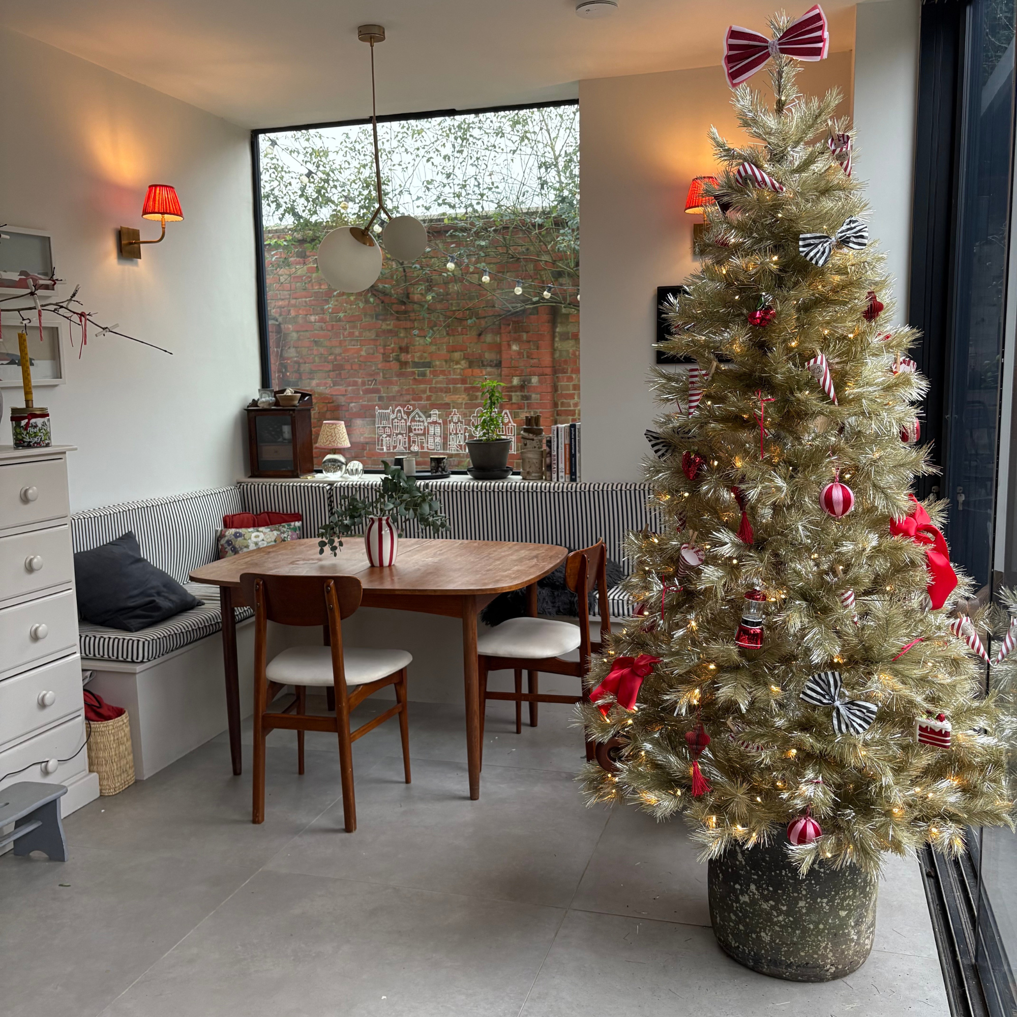 Close-up of Heather&#039;s gold tree adroned with red bows, striped baubles and food themed decorations.