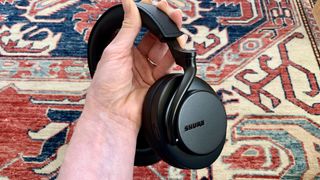 Shure Aonic 50 Gen 2 headphones held in a hand on multi-color background
