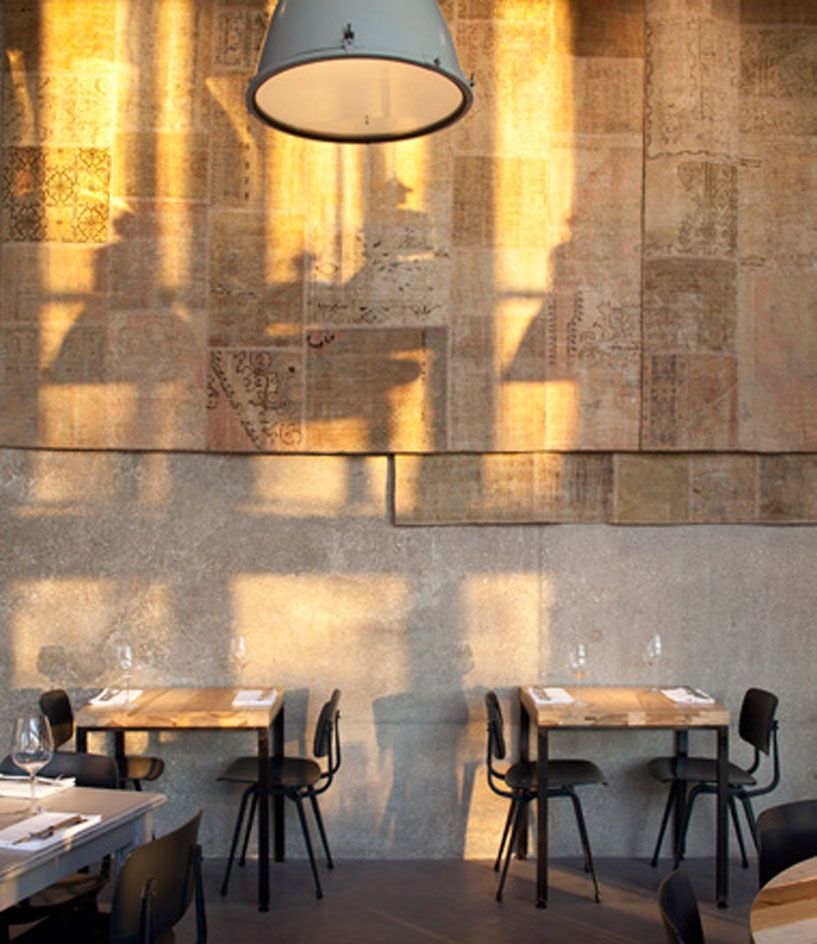 Single tables for 2 against wall, wooden table top with steel framework, black chairs, low hanging light fixtures