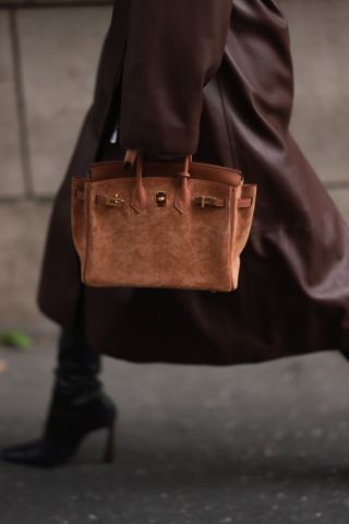 a woman at fashion week carrying a scuffed Hermes birkin bag