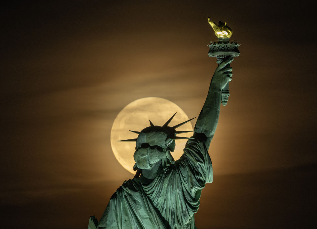 Der Vollmond scheint wie ein Heiligenschein hinter dem Kopf der Freiheitsstatue.