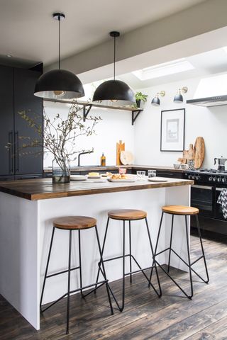 Central breakfast bar with wooden surface, wooden floor and bar stools