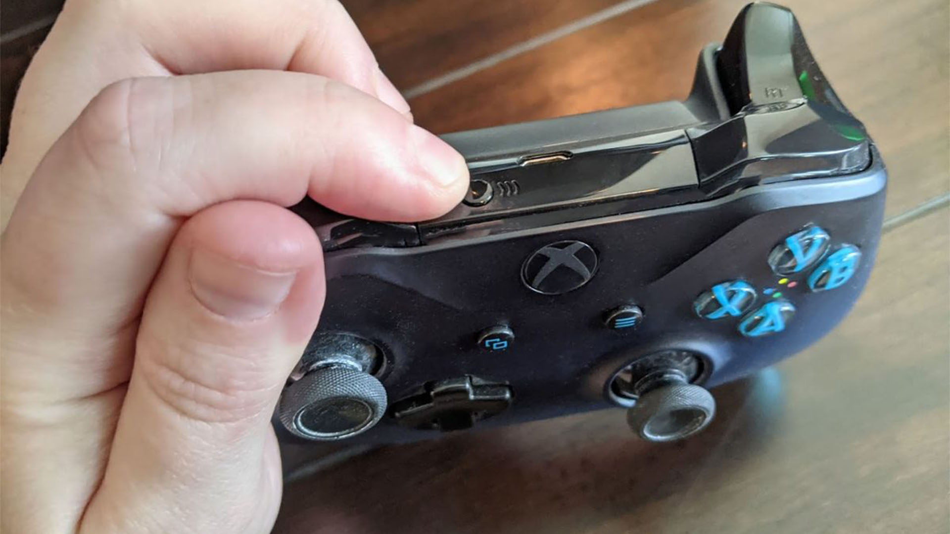 Контроллер Xbox One, на котором кто-то держит кнопку сопряжения в верхней части устройства.