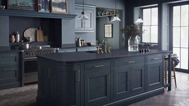 A dark kitchen with painted cabinets and island
