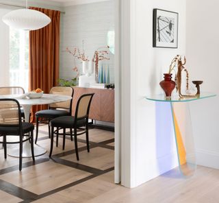 a dining room and hallway with a colorful glass console table