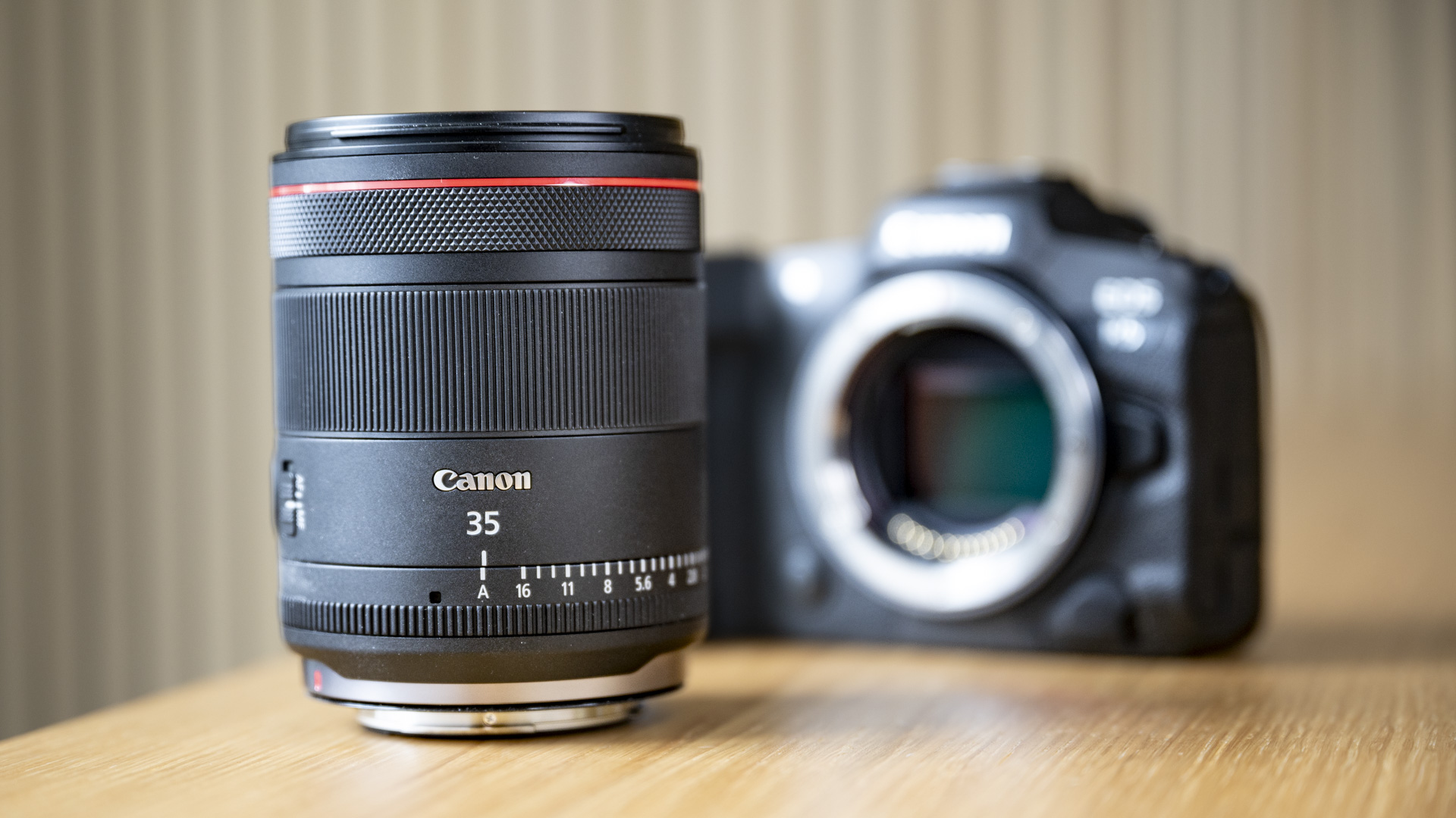 The Canon RF 35mm F1.4 lens on a wooden table in front a Canon EOS R5