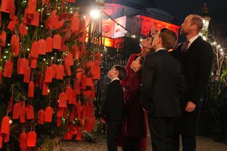 Prince William, Kate Middleton, and their children, Prince George, Princess Charlotte, and Prince Louis, at the "Kindness Tree" at the "Together At Christmas" Carol Service at Westminster Abbey.