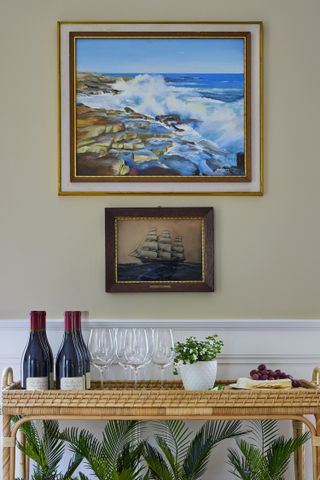 Two nautical prints sit on the wall above a drinks trolley