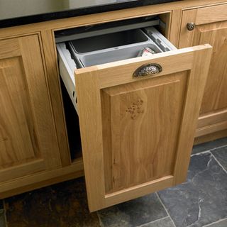 Wooden cabinet with bin and black flooring
