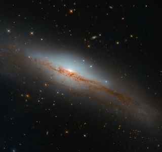 Looming some 135 million light-years from Earth in the constellation of Centaurus is the bright emission line galaxy NGC 3749, seen here in an image from the Hubble Space Telescope. Astronomers can learn a lot about a galaxy by studying its spectrum of light, particularly the wavelengths of light that are emitted or absorbed by elements it contains. NGC 3749 displays strong emission lines, which means that it is "bursting with star formation and energetic stellar newborns," the European Space Agency said in a statement.