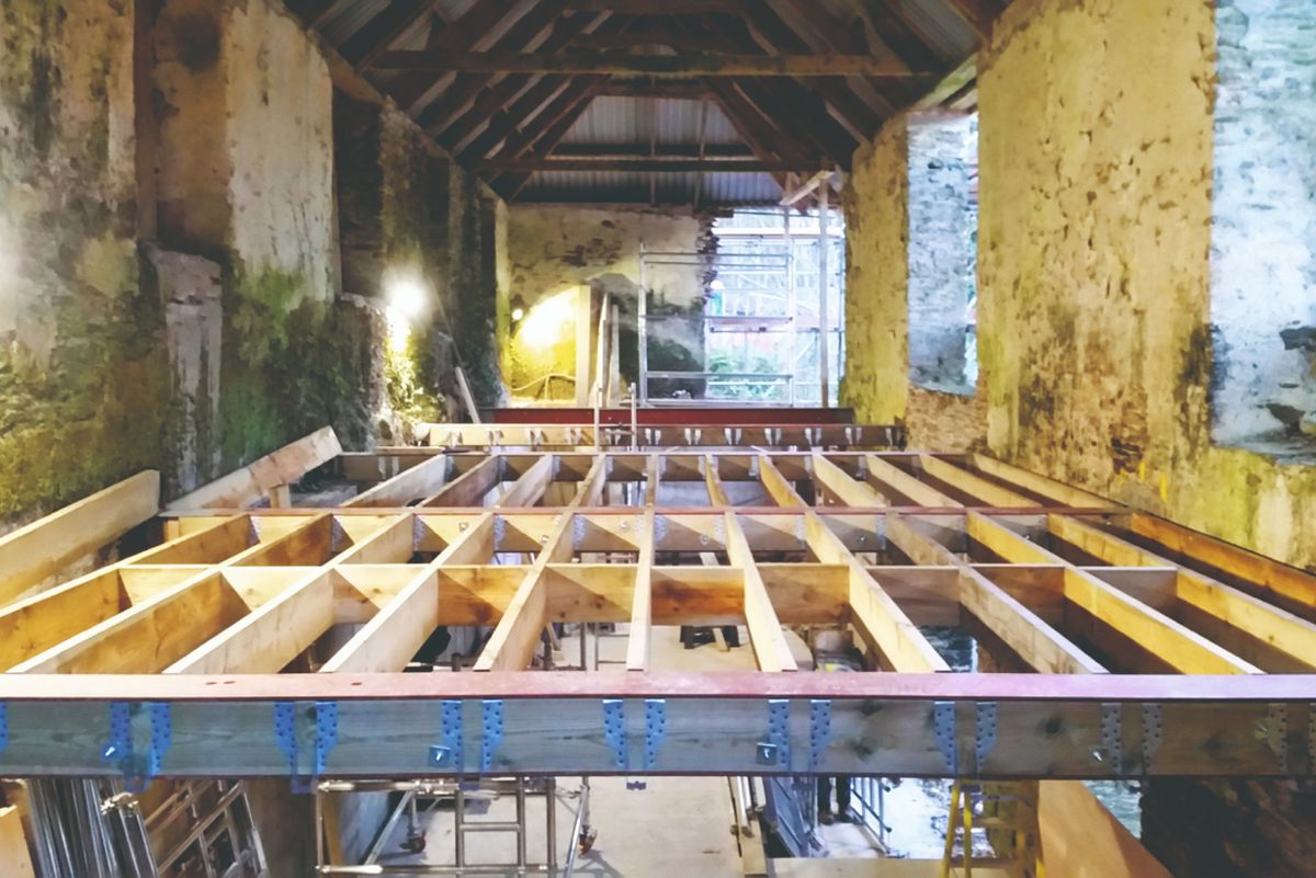 Oak frame foundations being constructed inside a stone barn