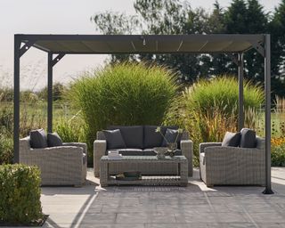 grey pergola with furniture and ornamental grasses
