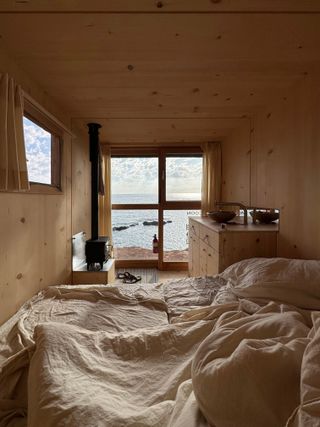 bed, wood burning stove and kitchen inside mobile wooden cabin