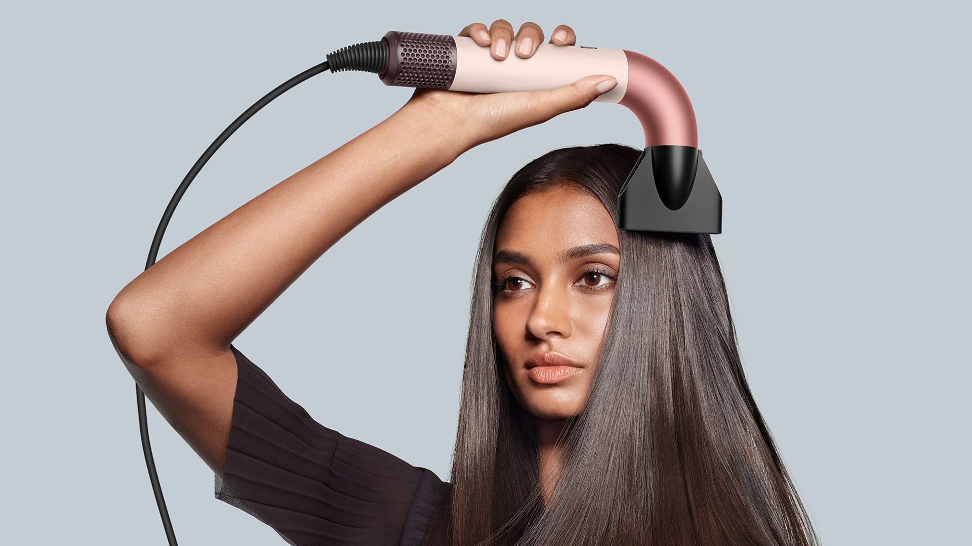 Woman using Dyson&#039;s Supersonic hair dryer to dry her hair