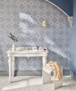 Blue bathroom with patterned blue and white tiles, white sink, blue painted walls