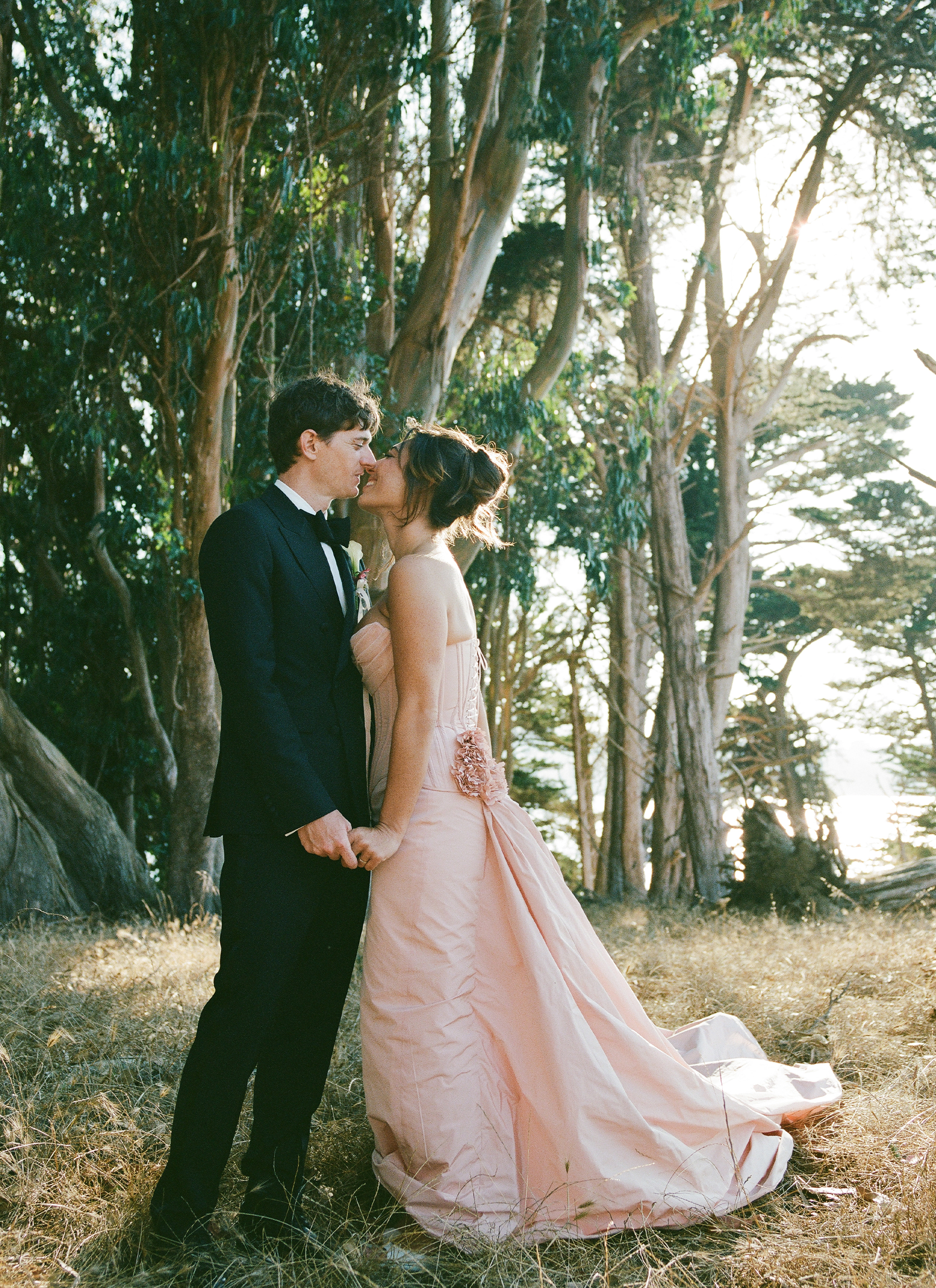 Charles and Hadley kissing under a tree.