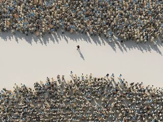 An overhead shot of a woman standing in the gap between two crowds of men