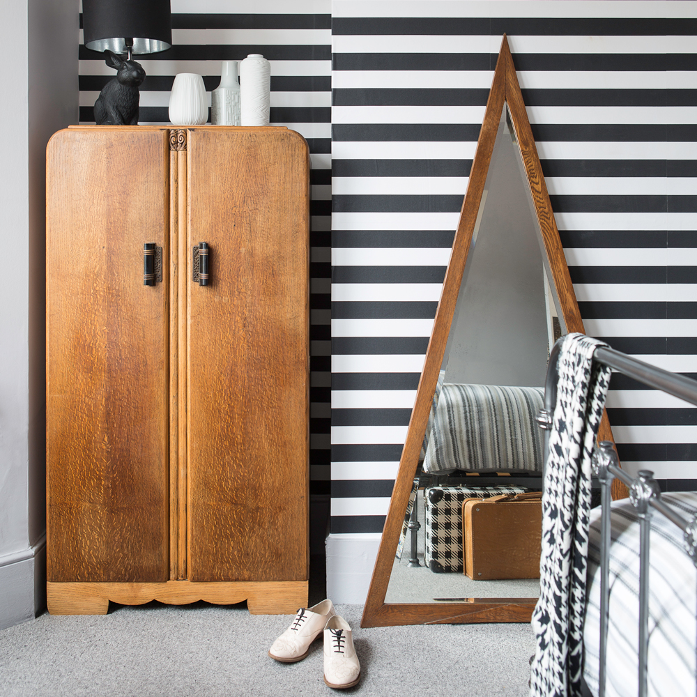 bedroom with monochrome stripe wallpaper and wooden cupboard
