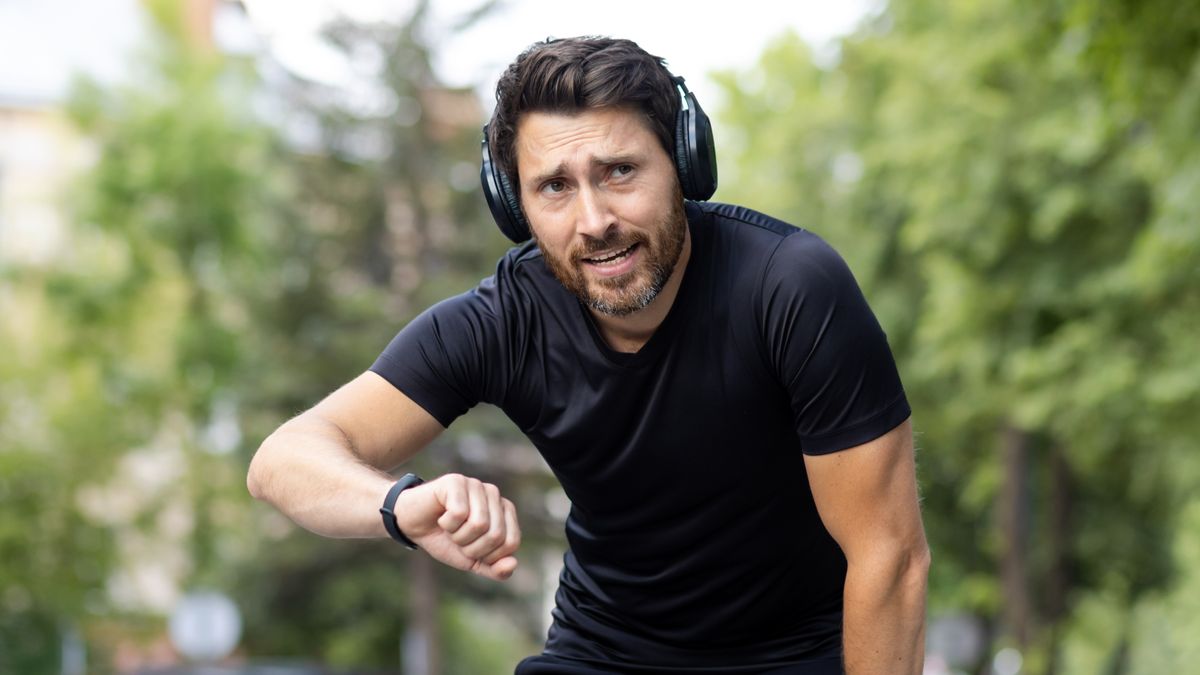 Tired man checking sports watch after a run