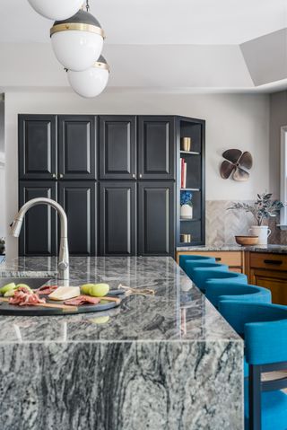 Black cabinets as an accent next to stained wood cabinetry and bright turquoise bar stools