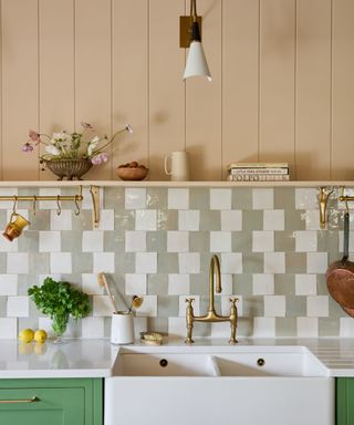 Green and white tiled groutless backsplash with white sink, wood panelling and gold tap