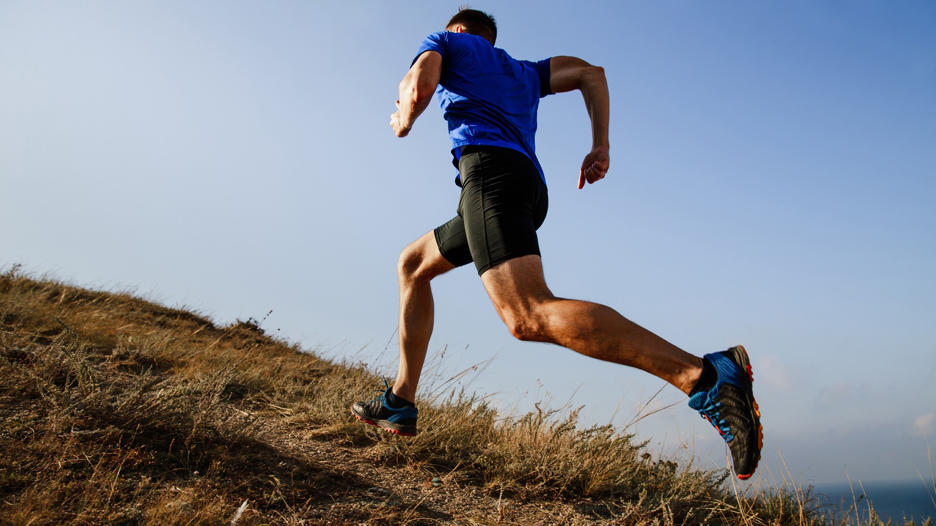 Man running uphill outdoors in the countryside in the sunshine