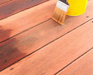 pot of deck stain and brush on deck