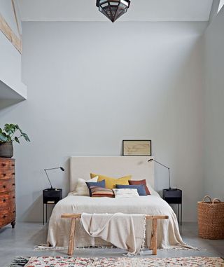 bedroom with white wall and bench and drawer units and rug