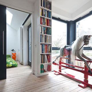 room with childs rocking horse and book shelfs and wooden floor