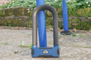 the stronghold D16 Max with angle grinder resistance lent against a blue bike rack