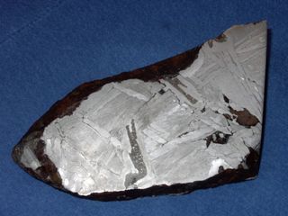 This 6-inch-wide (15 centimeters) fragment of the Seymchan meteorite found in Russia in 1967 is an iron-nickel pallasite. The long filament of dark grey material in the center is schreibersite.