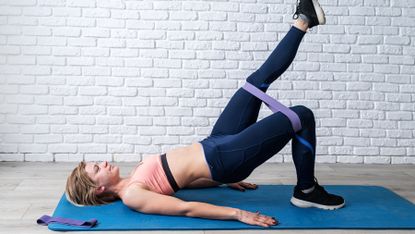 Woman performing a raised leg hip thrust with a resistance band